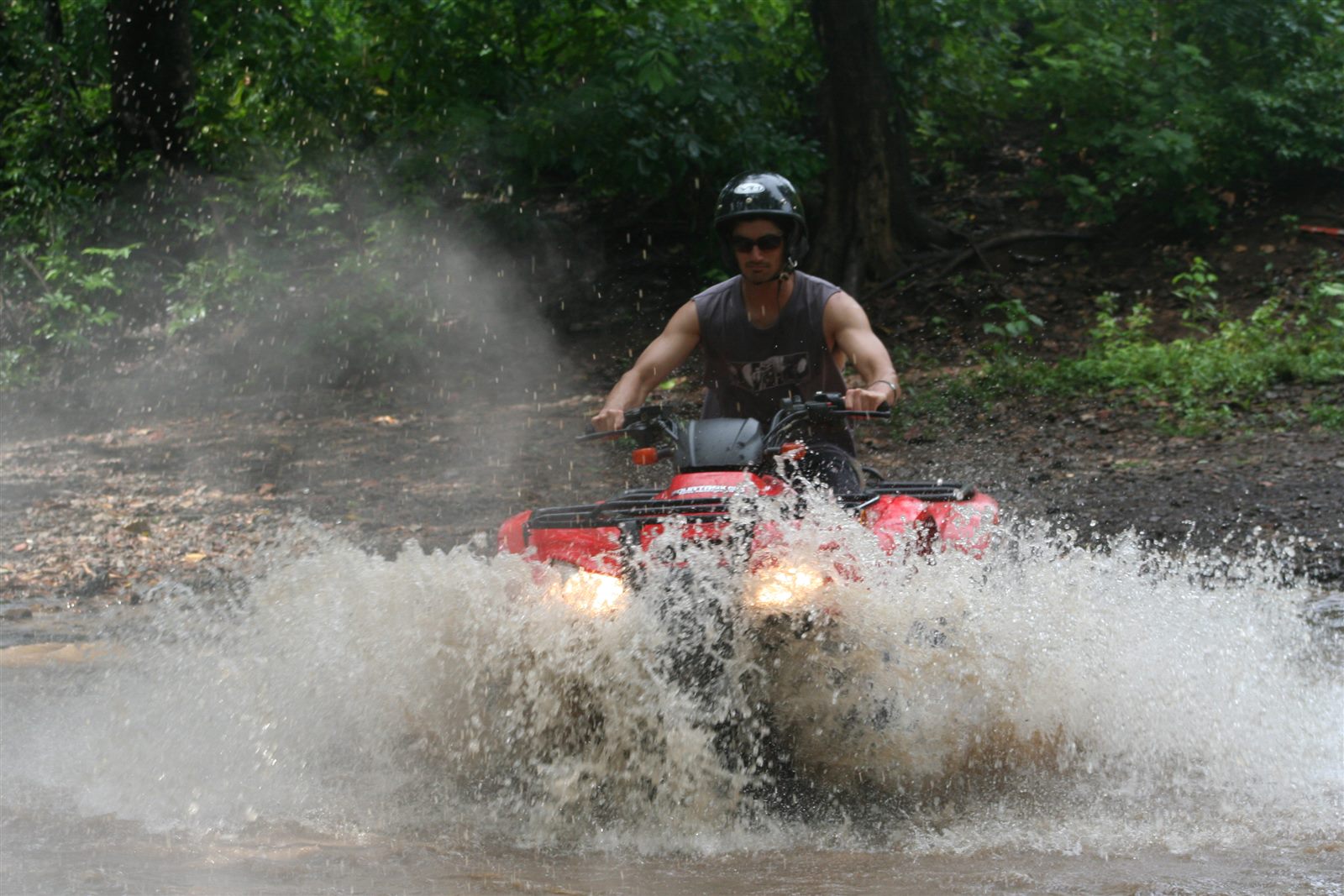 Guest riding a red ATV through a river crossing near Manuel Antonio